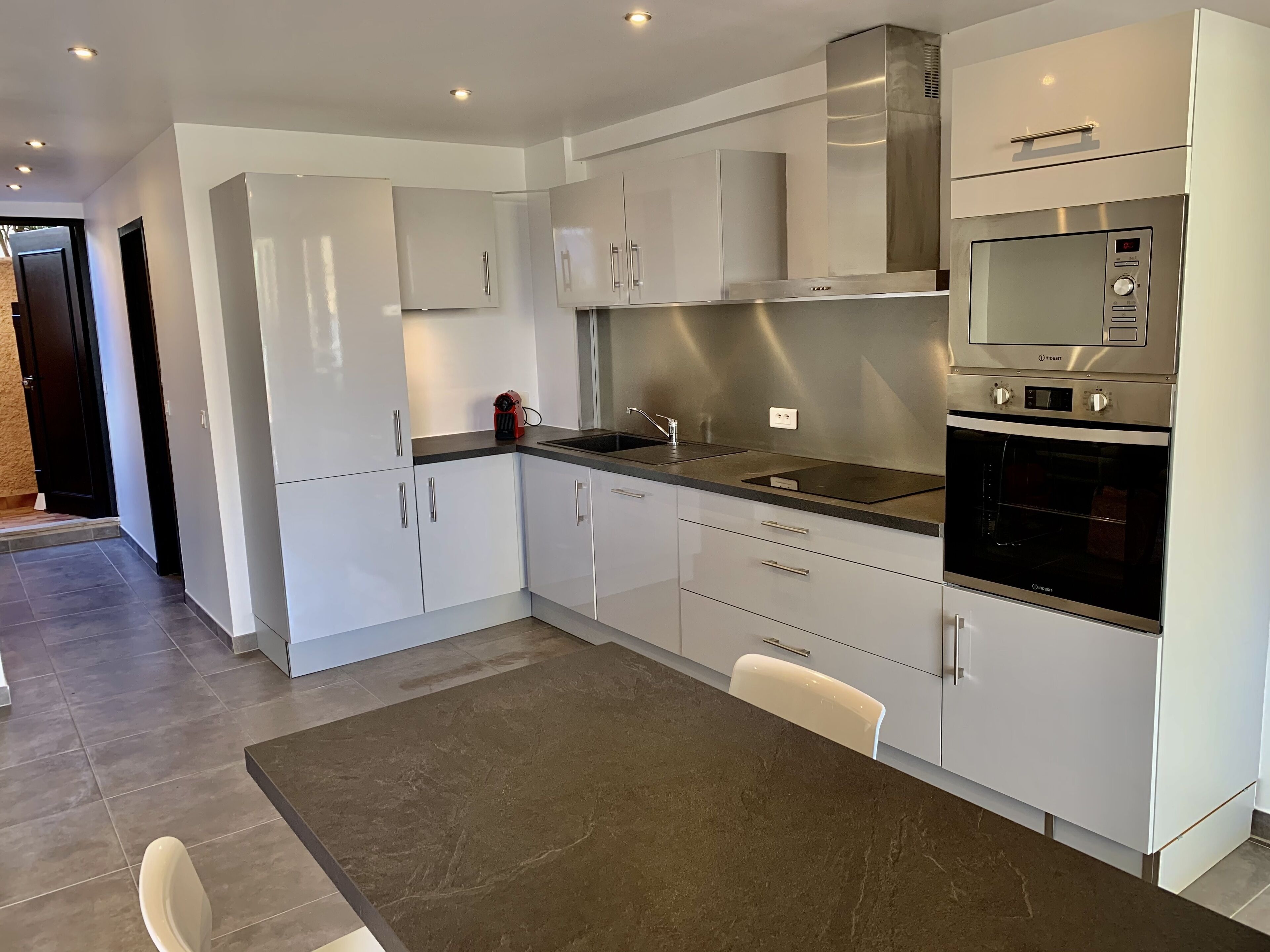 A modern kitchen with white cabinets, stainless steel appliances, and a dark countertop.