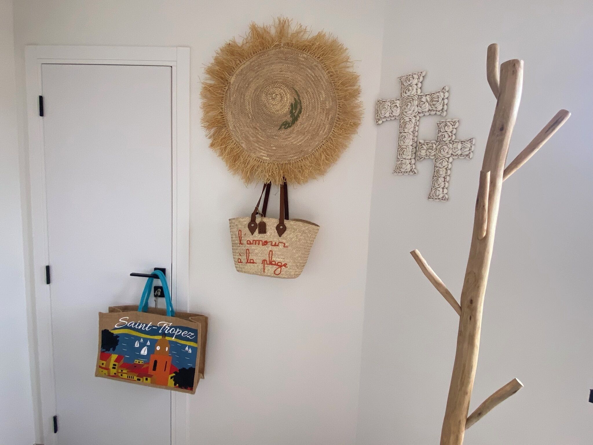 Una porta con una borsa blu appesa, un cappello di paglia, una croce di legno e una struttura in legno.