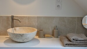 Ein Badezimmer mit einem großen Marmorwaschbecken, einem Handtuchhalter und einem Spiegel.