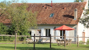 Ein rustikales Haus mit Ziegeldach, Schornstein und einem kleinen Fenster.