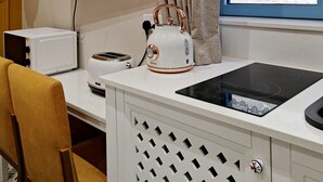 Una kitchenette compacta equipada con microondas, tostadora, hervidor y placa de inducción.