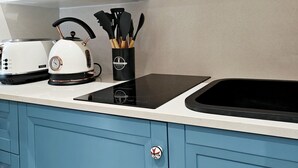 Een moderne keuken met witte kasten, een zwart inductiekookveld, een broodrooster en een magnetron.