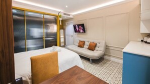 Een hotelkamer met een bed, een slaapbank, een televisie en een bureau.