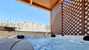 A hot tub area with a wooden pergola overhead, a stone wall, and a lattice screen. - Zebbuga guest house Malta 5 (Ħaż-Żebbuġ)