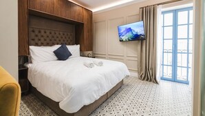 A hotel room with a large bed, a television mounted on the wall, and a view of the outside through a window. - Zebbuga guest house Malta 6 (Ħaż-Żebbuġ)