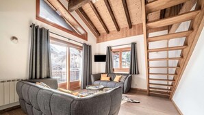 Een moderne woonkamer met een ingebouwde bank, een klein rond tafeltje en een aan de muur bevestigde televisie.