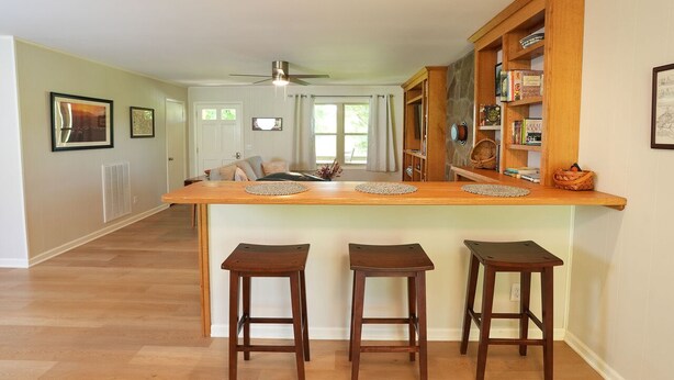 Una cocina con una isla de madera, tres taburetes y una estantería empotrada.