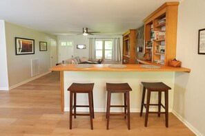 Una cocina con una isla de madera, tres taburetes y una estantería empotrada.