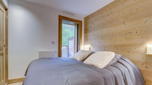 A bedroom with a bed, wooden walls, a door, and a window. - 200m from ski slopes, Ground floor, terrace, tv, 42m², Morzine (Morzine)