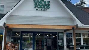 Außenansicht eines Whole Foods Market Geschäfts mit einem dreieckigen Dach und blauem Himmel im Hintergrund.