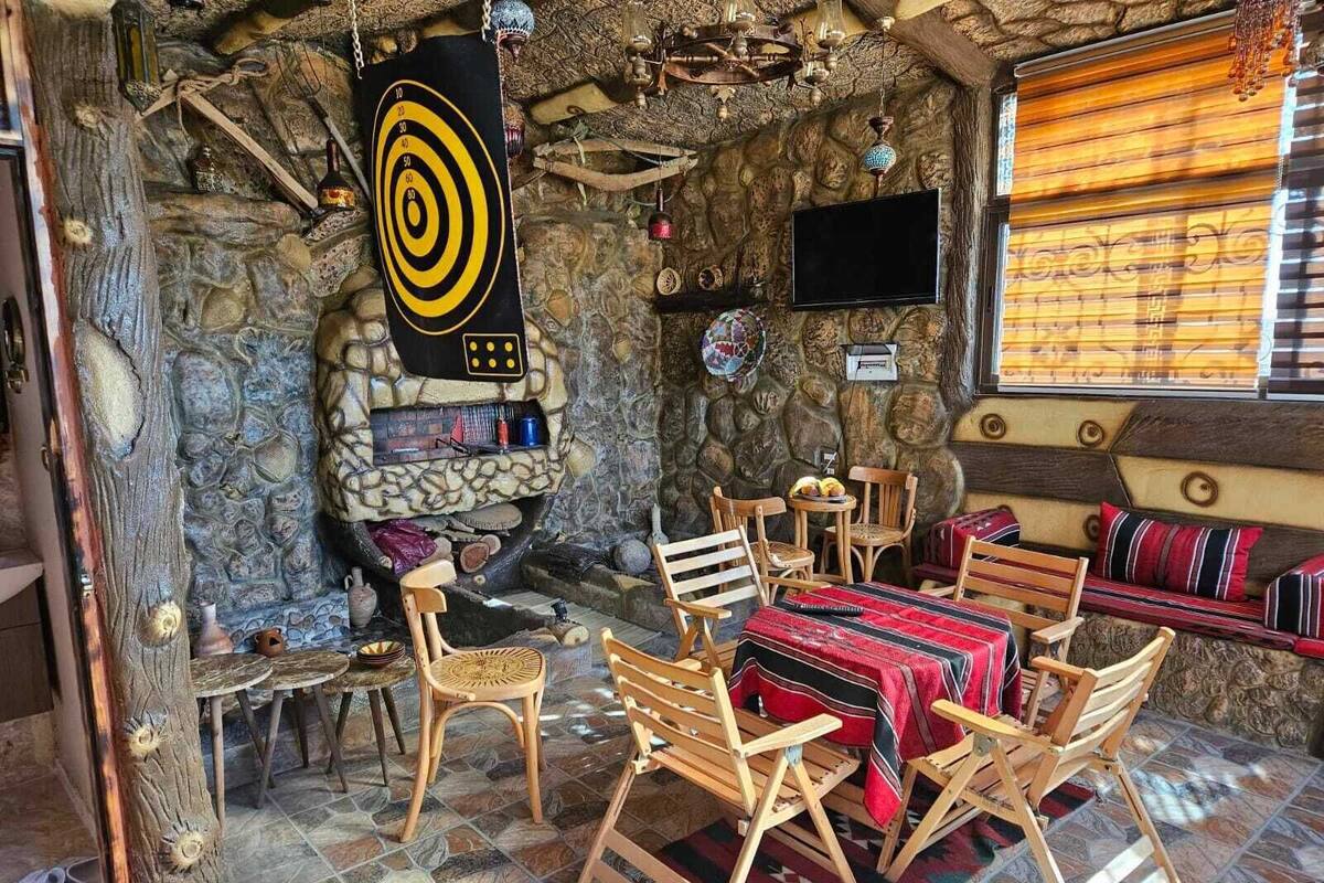A rustic interior with a stone fireplace, wooden furniture, and a television mounted on the wall.