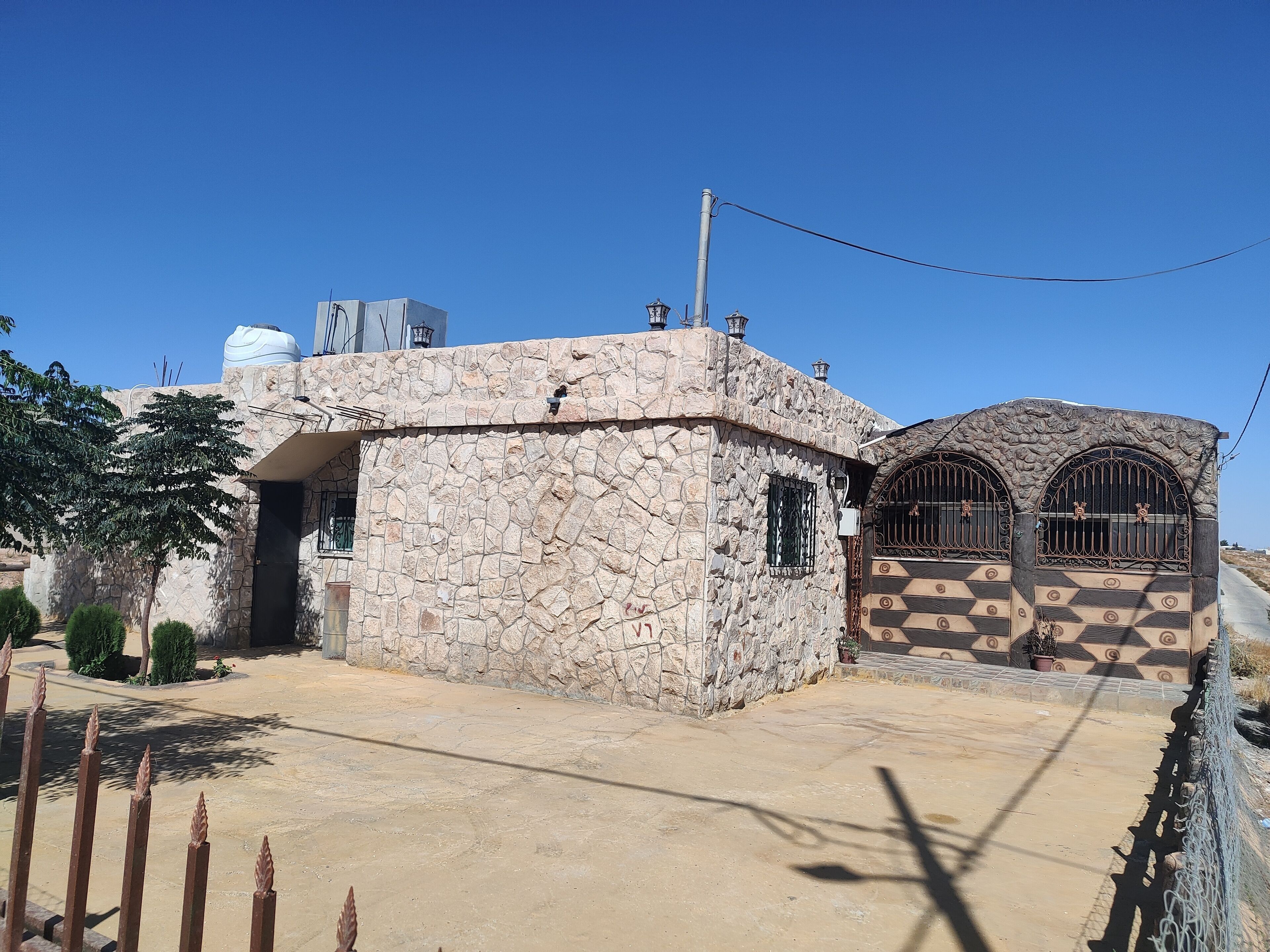 Un edificio de piedra con una entrada pequeña y un área vallada.