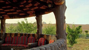 A covered outdoor seating area with patterned cushions and a view of a field. - Petra dad farm (Shamakh)