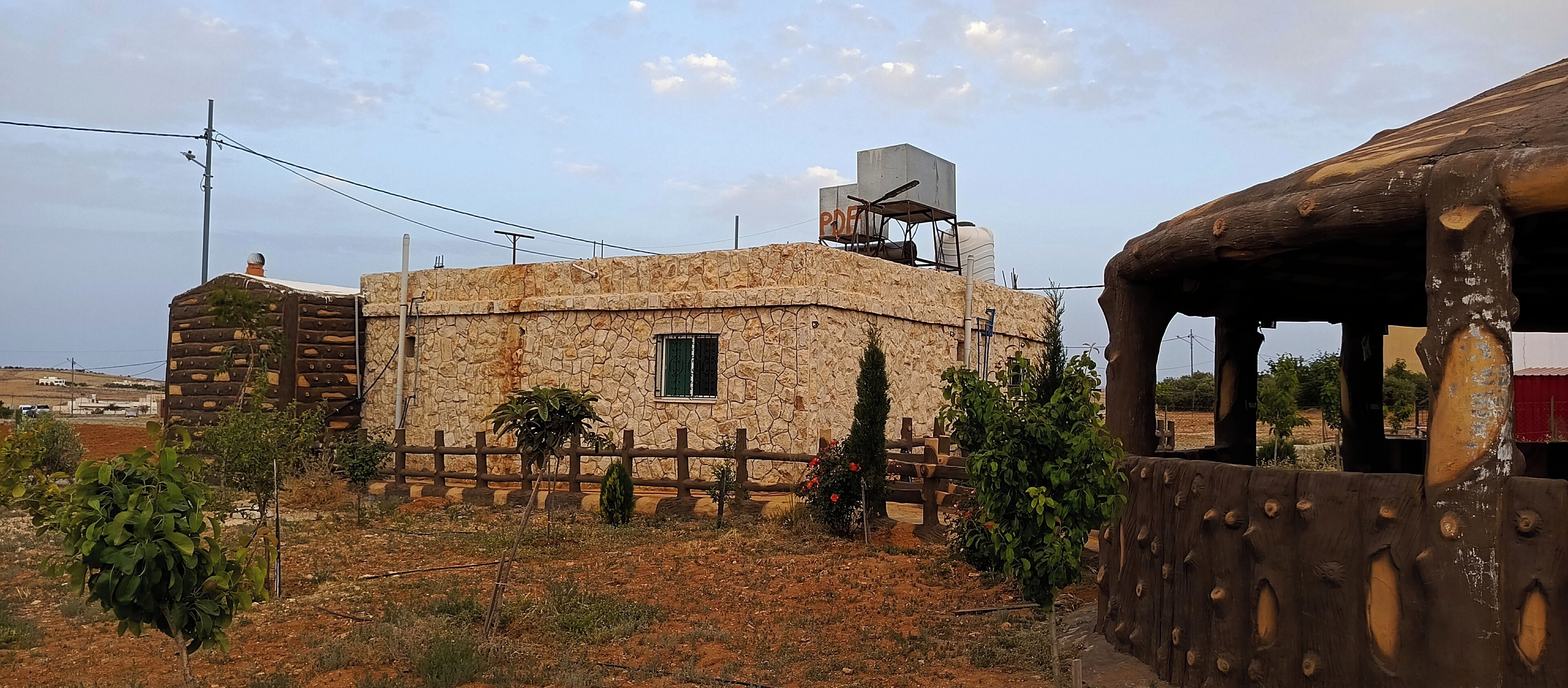 A rustic stone building with a small window and a water tank on the roof.