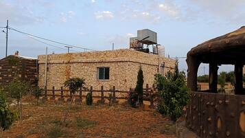 A rustic stone building with a small window and a water tank on the roof.