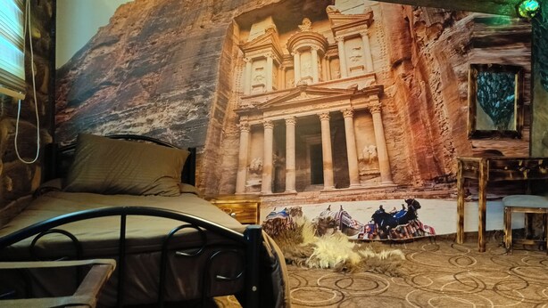 A room with a bed, a small table, and a camel decoration. - Petra dad farm (Shamakh)