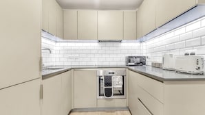 Una cucina moderna con mobili chiari, piastrelle bianche a metro e elettrodomestici in acciaio inossidabile.