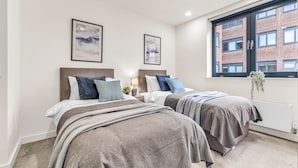 Una camera da letto moderna con due letti, una grande finestra e opere d'arte alle pareti.