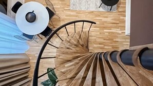 A spiral staircase with a modern design, leading to a living area with a sofa and a coffee table.