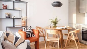 Une cuisine moderne avec des meubles en bois, une table à manger avec des chaises et un luminaire suspendu.