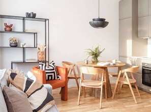 A modern kitchen with wooden cabinets, a dining table with chairs, and a hanging pendant light. - TurnKey | Republic Square Apartment III (Praha 1)