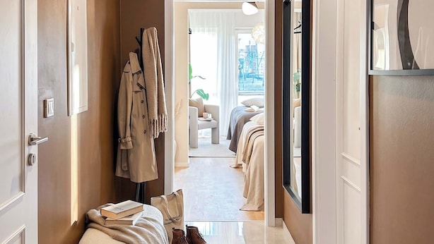 A hallway with a bench, coats, and a bed in the distance. - TurnKey | Republic Square Apartment I (Praha 1)