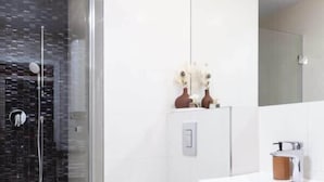 A modern bathroom with a glass-enclosed shower, a white toilet, and a white sink with a mirror above. - TurnKey | Republic Square Apartment I (Praha 1)