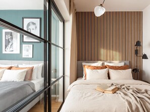 Un dormitorio moderno con cama, lámparas de noche y un ventanal con persianas.