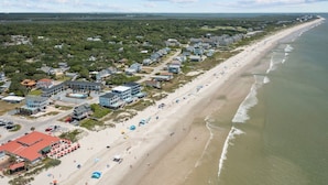 An aerial view of a coastal area with a beach, houses, and a road.