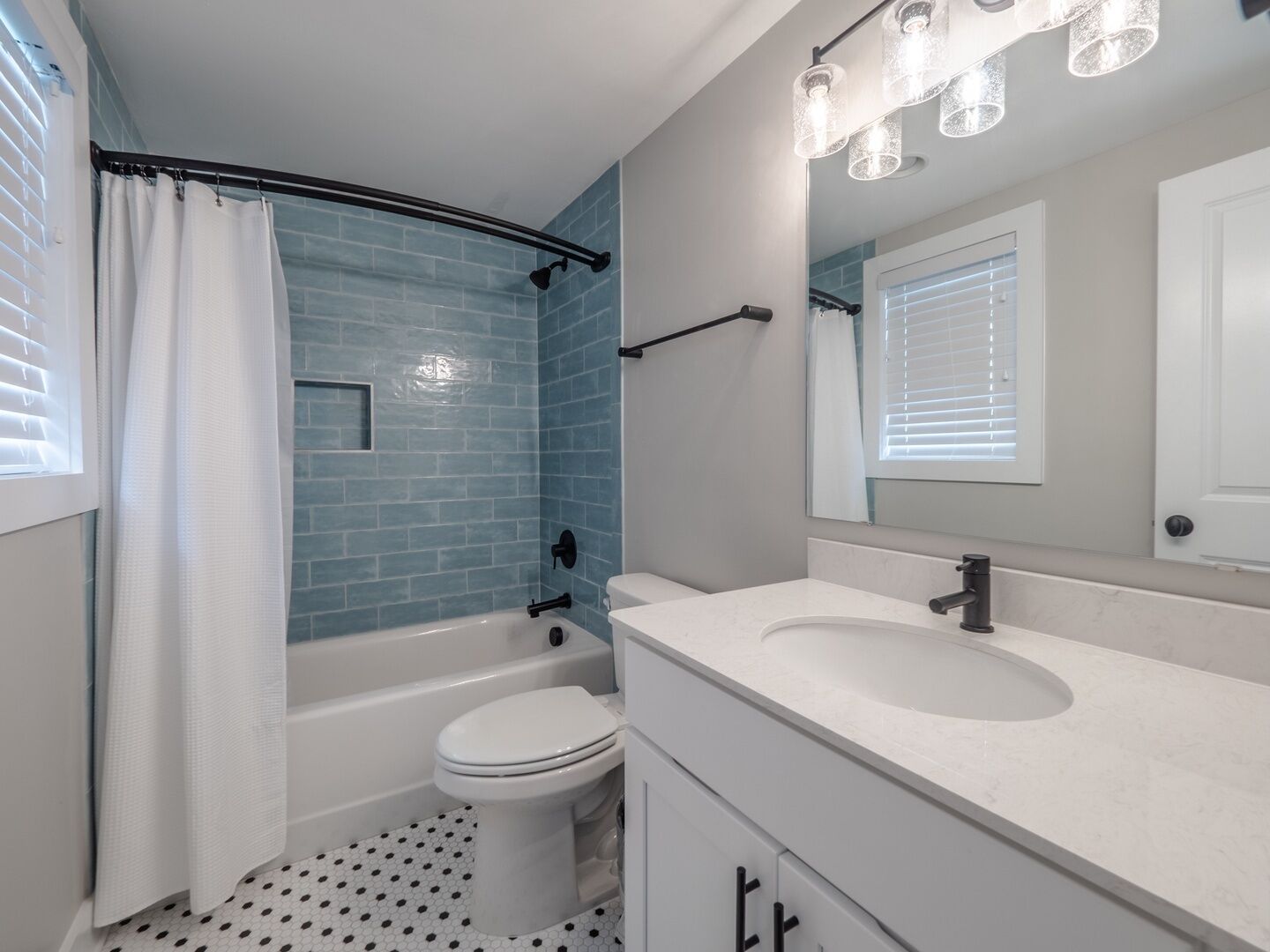 A bathroom with a bathtub, toilet, and vanity with a mirror.