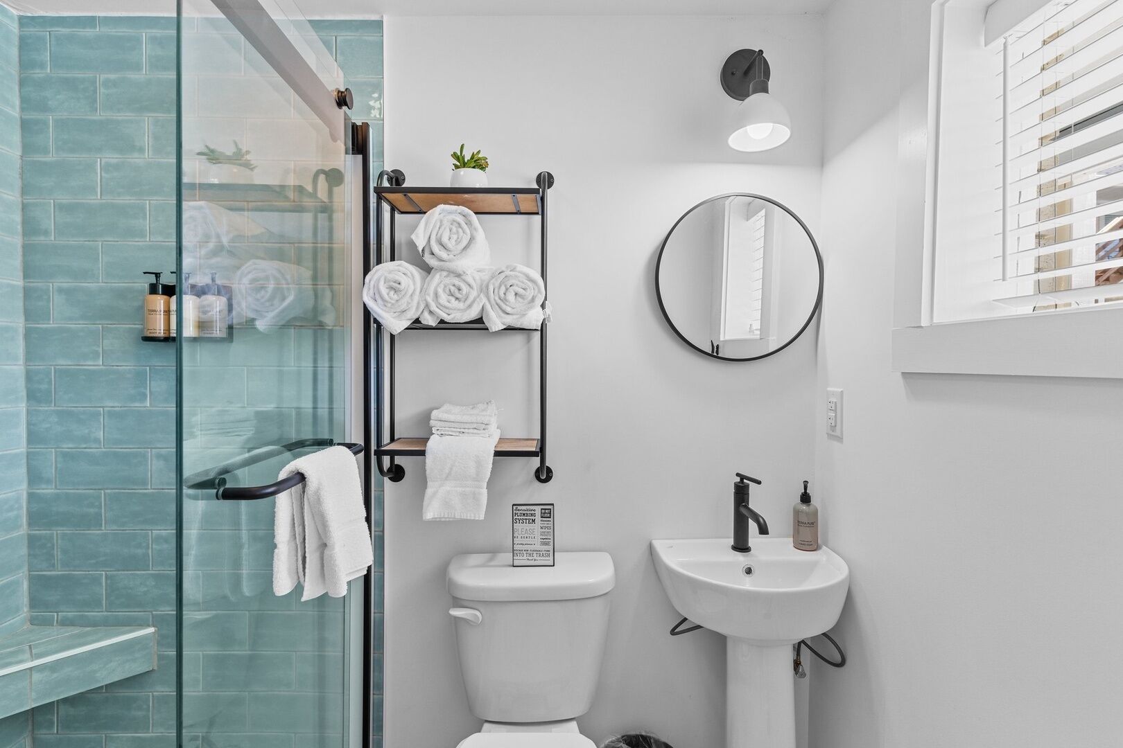 Un baño moderno con cabina de ducha de vidrio, inodoro, lavamanos y toallero con toallas dobladas con esmero.