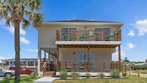 A two-story building with a balcony, a staircase, and a small garden area.