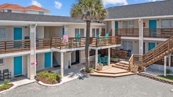 A multi-story motel with a central courtyard, outdoor seating, and a flag.