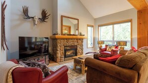 Una sala de estar acogedora con chimenea de piedra, televisor y asientos cómodos.