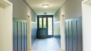 Ein Flur mit einer Tür am Ende, gesäumt von Paneelenwänden und einer Deckenleuchte.