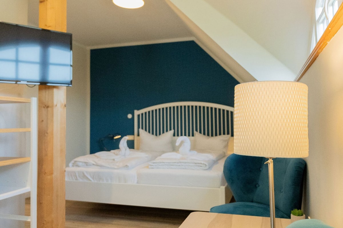 A bedroom with a bed, a bedside table, a chair, and a lamp.