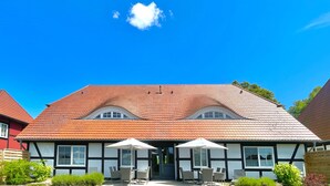 Ein traditionelles Fachwerkhäuschen mit rotem Ziegeldach, zwei Fenstern und einer Tür.
