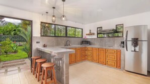 Een moderne keuken met een groot eiland, houten kastjes en een roestvrijstalen koelkast.
