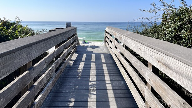 A wooden boardwalk leading to a beach with clear skies.