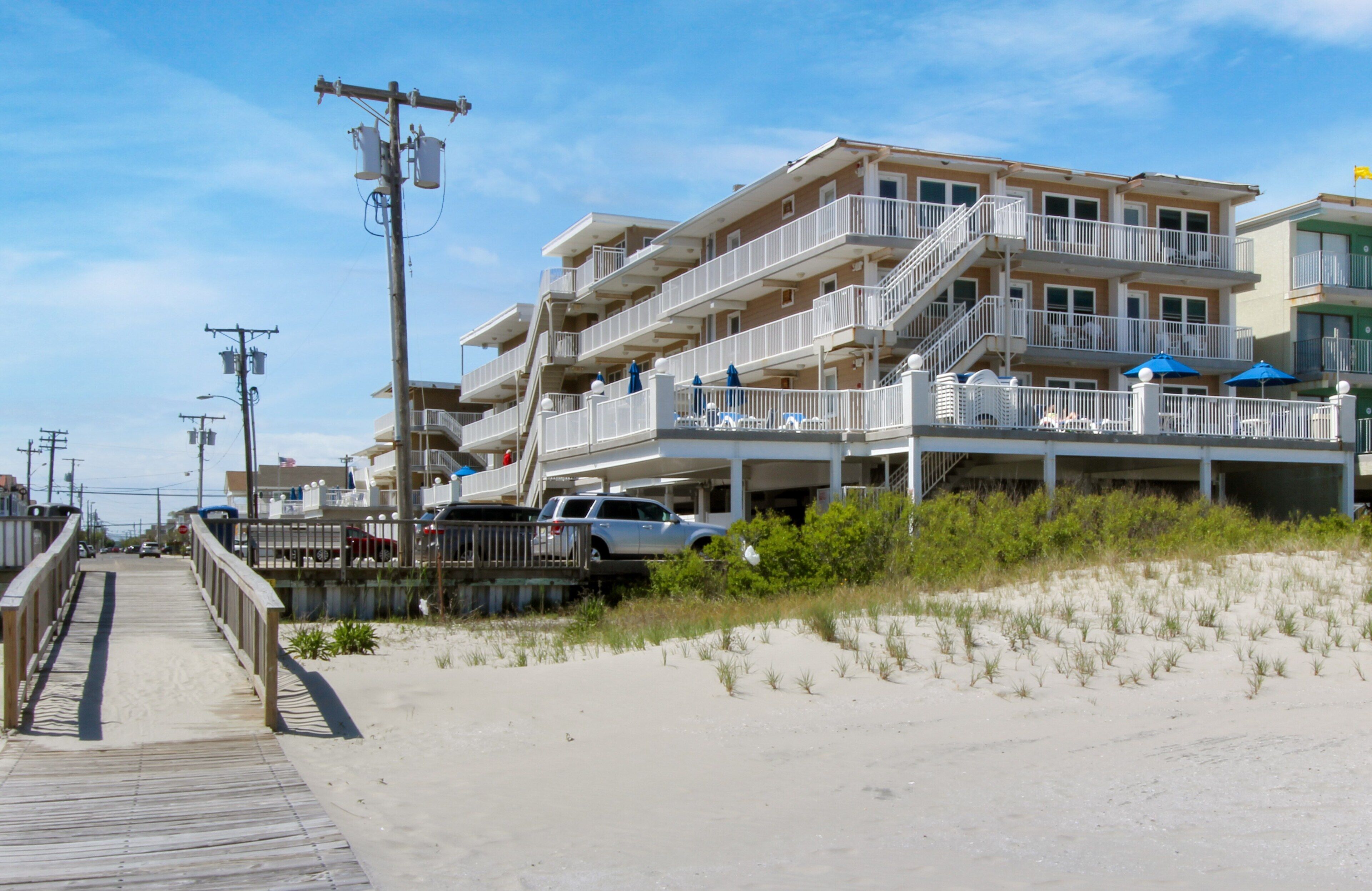 Un hôtel situé en bord de mer, doté de nombreux balcons, d’une promenade en bord de plage et d’une végétation côtière.