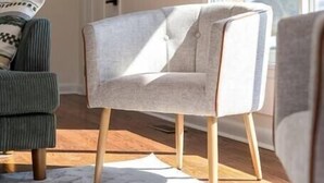 Una sala de estar moderna con un ventanal grande, un sillón gris y un sofá verde.