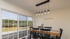 Comedor con suelo a cuadros, mesa de madera, sillas negras y vistas amplias a través de ventanas grandes.