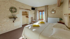 A bedroom with a large bed, a wooden headboard, a window with curtains, a small table with a lamp, and a wall-mounted TV. - La Maison de Charlotte (Amberre)
