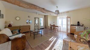 A spacious living area with a wooden ceiling, a dining table with chairs, a sofa, and a coffee machine. - La Maison de Charlotte (Amberre)