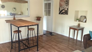 A kitchen with a wooden bar stool set, a potted plant, and a mirror on the wall. - La Maison de Charlotte (Amberre)
