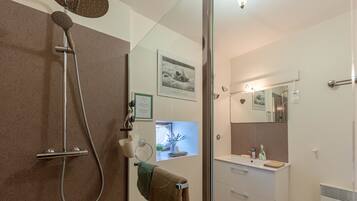 Un bagno moderno dotato di doccia, lavandino e specchio.
