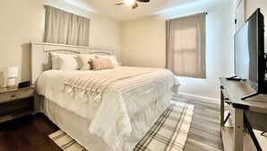 A bedroom with a bed, a nightstand, a TV, and a ceiling fan. - Cozy home. Newly remodeled and easy access to all that Grand Rapids has to offer (Grand Rapids)