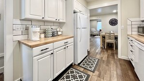 A modern kitchen with white cabinetry, a refrigerator, a coffee maker, and a microwave. - Cozy home. Newly remodeled and easy access to all that Grand Rapids has to offer (Grand Rapids)