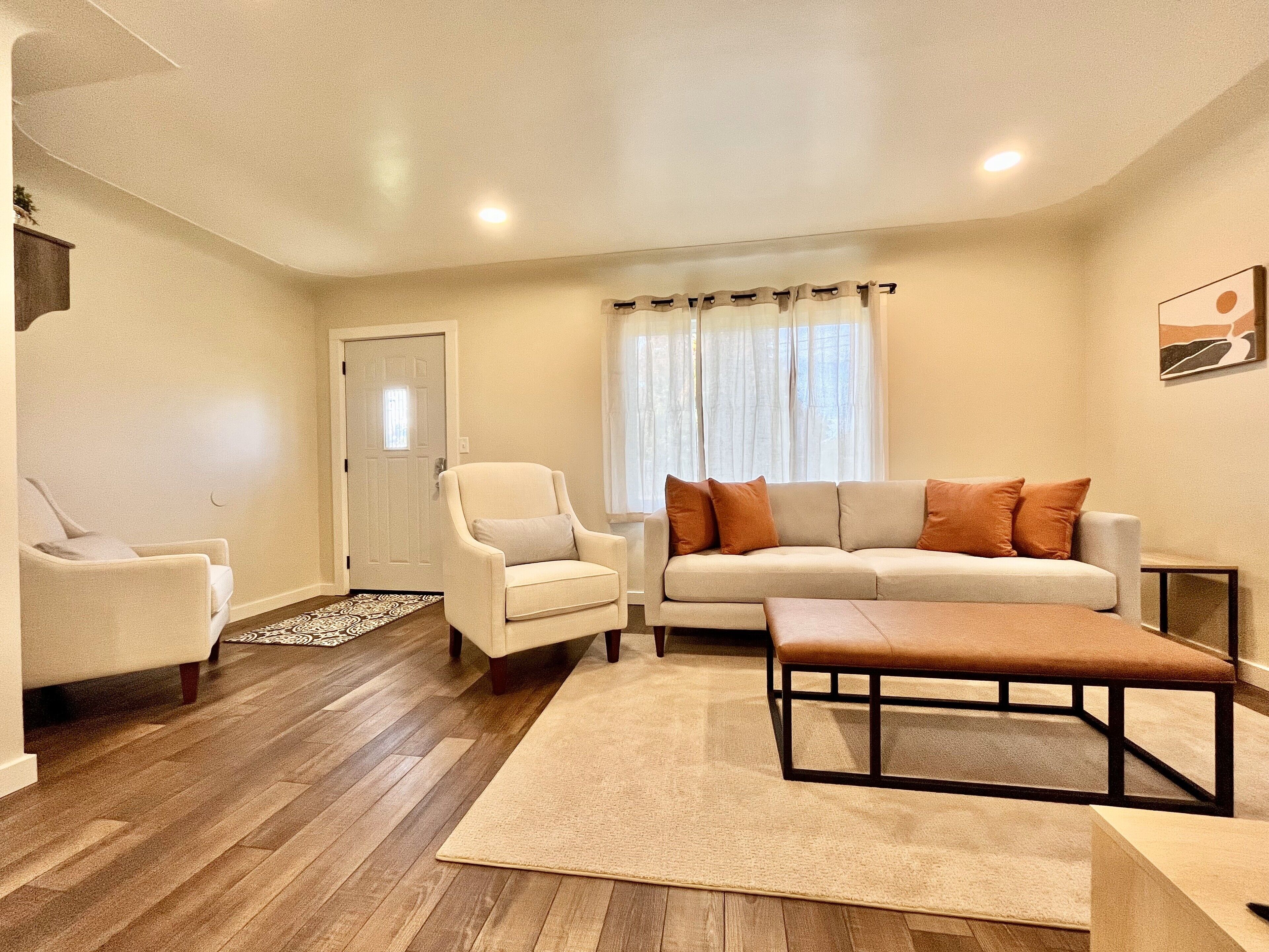 A living room with a sofa, armchairs, a coffee table, and a rug.