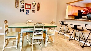 Un coin repas avec une table et des chaises, une cuisine en arrière-plan et des éléments décoratifs sur les murs.